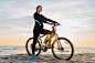 Free photo young attractive slim woman riding bicycle, sport on morning sunrise summer beach in sports fitness wear, active healthy lifestyle, smiling happy having fun