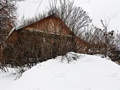 在冬天下雪的背景上有一扇破窗户的废弃旧房子