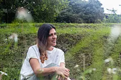 一位拉丁妇女坐在公园的草地上望着地平线。正常的新概念