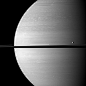 The moon Tethys occupies the right foreground of this Saturnian scene. This view from NASA's Cassini spacecraft looks toward the anti-Saturn side of Tethys and toward the northern, sunlit side of the rings from just above the ringplane.