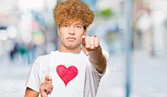年轻帅气的男子拿着纸用红心指着镜头和你，手势，正面自信的手势