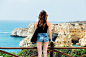 woman standing in front of fence looking at rock formation