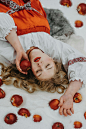 Free A woman in traditional attire with red apples lies peacefully on snow. Stock Photo