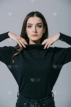 美丽时尚的女人摆姿势在黑色毛衣，孤立在灰色