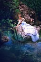 woman in white dress sitting on rock in water