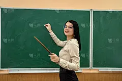 快乐的年轻老师在学校的教室里靠近黑板。