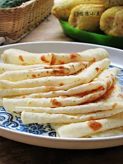 家乡味传统主食【烙馍】的快手做法 食 材：普通面粉500g；开水110g，凉水110g，食用油少许。 1、面粉中倒入开水，快速搅拌面粉成面絮，静置三四分钟后，然后加入凉水，继续搅拌。将面絮揉成光滑的面团，揉的过程中手上加入少许食用油，揉砸进去。揉好的面团光滑有弹性，上面盖一块干湿布，饧发30分钟。饧好的面团变得更软，再次揉匀，分切成合适的面块。揉成长圆条形，按照做饺皮的方法将其切成小面剂子。 2、面剂子稍整圆，按扁，然后两两分成一组，并在其中一个上刷油，然后将另一个叠放上去。擀面杖擀叠好的面剂子，擀成圆