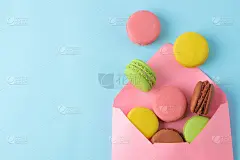 马卡龙。装在信封里的法国彩色杏仁饼干。小的法国甜蛋糕在明亮的蓝色背景。甜点。糖果。前视图。