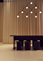 This may contain: a table with four stools under a chandelier in front of a curtain