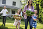 Photograph Family Party. Parents And Children Walking Across The Lawn Carrying Flowers, Fresh Picked Vegetables by Mint Images on 500px