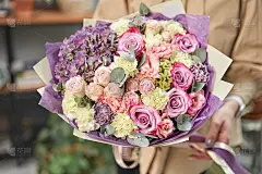 现代花卉商店。花店的工作完成了。可爱的一束混合鲜花在女人的手里。送新鲜的切花。