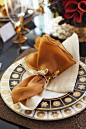 Linens in warm fall colors are given a playful addition of a gold napkin ring with a bird on it. - Traditional Home ? / Photo: Colleen duffley