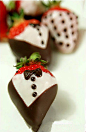巧克力礼服草苺 食材：80克白巧克力、50克黑巧克力、草莓、食用银糖珠、彩糖粒、草莓糖粉、裁成小块的烘焙油纸（可用锡纸代替） 做法：1)将黑、白巧克力分别隔热水融化。将白巧克力分出30克，拌入草莓糖粉调成粉红色。2)将草莓粘上一层巧克力，放烘焙油纸上待凝固后再粘上一层，。再按创意粘上其他颜色的巧克力和糖珠等食用装饰。3)将黑巧克力液倒入裱花袋里，前端剪出极小的口，在巧克力草莓上挤出领结、纽扣。糖珠等装饰材料趁巧克力还未凝固时粘上即可。