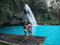 在宿务岛碧绿的河水中，一对情侣在竹筏上独自旅行