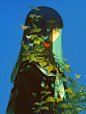This may contain: a woman's head is covered with leaves and butterflies as she stands in front of a blue sky