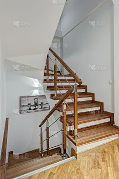 大房子走廊的正面视图，二楼有木楼梯，白色墙壁。内饰为白色，棕色和米色。