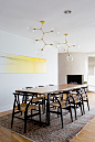 Mid century modern dining room with white walls, yellow art and gold light fixture