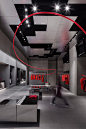 This may contain: a person walking through a room with red shirts hanging on the walls and black flooring