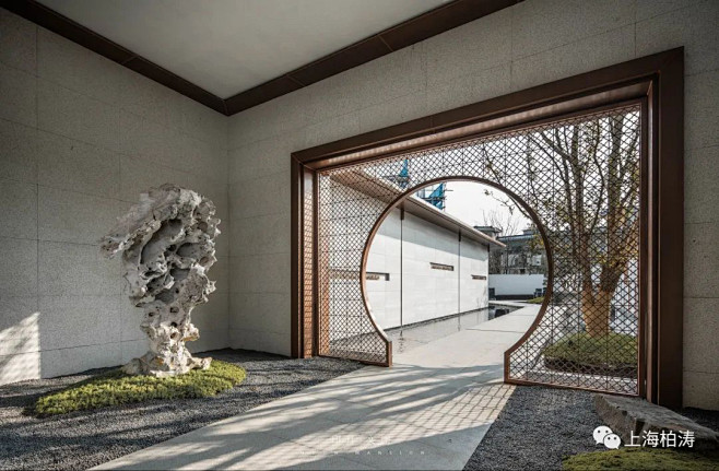 阳光城·印月文澜 月洞之门 光影流入屏风，指引来客进入廊道，景象逐渐丰富，石质路面两侧的静水面、墙上诗文引人入胜。