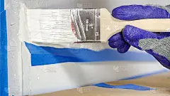 特写画家的手与手套油漆墙壁边缘与刷子。以上成型、踢脚板手绘。