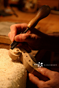 Hand of violin maker working on scroll of violin.