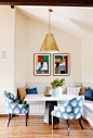 Brass and blue breakfast nook with abstract art, industrial lighting, and many pillows