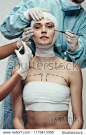 Portrait of young woman wrapped in medical bandages while beautician doctors with syringe and scalpel near her face. Female having a face lift surgery at cosmetic clinic.