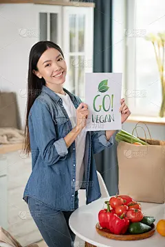 长头发的年轻女孩手里拿着海报在厨房里。