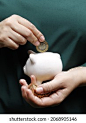 hand of a woman depositing mexican money in a piggy bank 库存照片