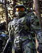 a man in a futuristic suit and goggles standing in the woods with trees behind him