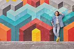 年轻女子靠在彩色的墙上