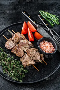 把肉串和蔬菜放在盘子里烤。黑色背景。俯视图
