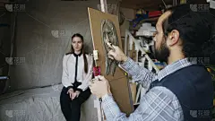 技艺精湛的雕刻家在画室里用油画布上的橡皮泥创作出摆姿势的女性模特的脸