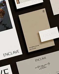 这可能包含：棕色桌子上的一些白色和黑色名片，中间放着鲜花，其中一张名片上有一个写着“enclave”的姓名标签