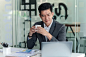 front-view-asian-businessman-drinking-coffee-while-looking-laptop-office_37714-1217