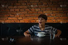 一个微笑的少年在砖/灰色墙纸前的肖像。它被自然光和背景中的黄光照亮。