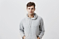 Handsome attractive european man in gray hoodie, with hands in pockets, look pleased , has good mood as comes home after work. good-looking male student poses . Free Photo