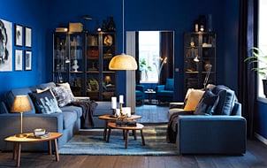 蓝色的客厅内放着玻璃面橱柜和两张蓝色沙发...