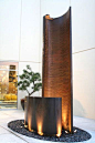 Water Fall Fountain Sculpture with rain curtain in a courtyard,  location is in City of Industry, CA   made from - Ridged and smooth copper with bronze patina