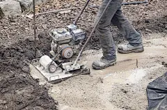 操作动力板压实机的工人