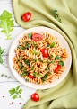 Fusilli pasta with tomato sauce, cherry tomatoes, lettuce and herbs Premium Photo