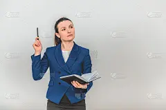老师站在那里，打开笔记本，用笔尖指向上面，叫大家注意她在说什么，脸上带着若有所思的表情。