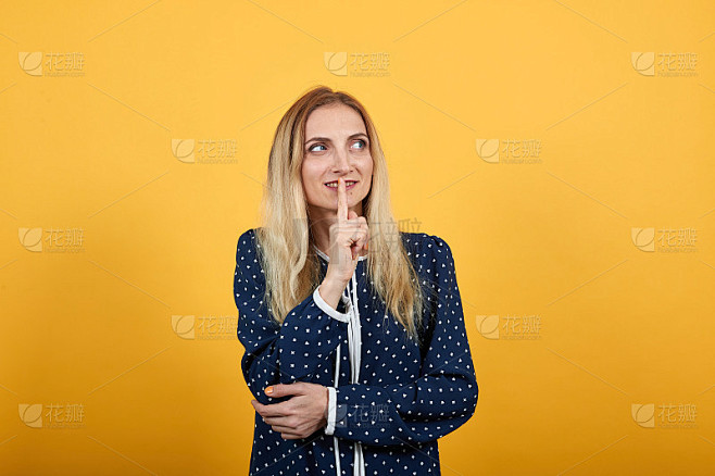 美丽的年轻女士把手指放在嘴上，做嘘的手势，抬头看