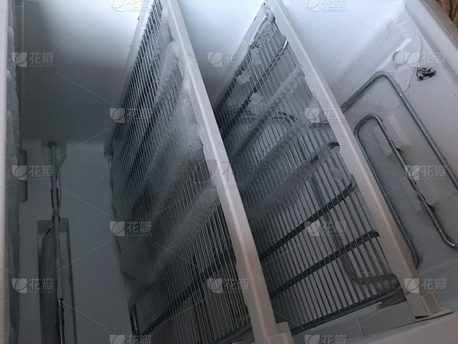 带门的冷冻室。覆盖着雪和冰的冰箱打开解冻。在冰箱里，雪和冰正在融化，冻结在墙上和架子上。