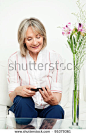 Smiling senior woman sitting on couch with smartphone