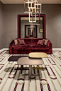 Red velvet touch reading room | oasis rooms | luxury interior design and italian furniture  : living room with soft-hues wall covering turned on by a red velvet sofa, the perfect relaxing and reading corner; bookcases and small tables complete the interio