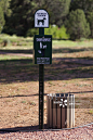 A sign and bin for pet waste in a park