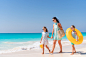 Adorable little girls and young mother on white beach