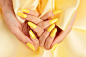 黄色丝绸织物上涂有黄色指甲油的女性手的免费照片特写镜头