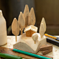 This may contain: a wooden toy house sitting on top of a table next to pencils and markers